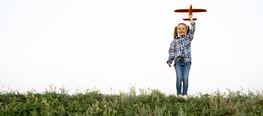 carefree adopted Caucasian girl standing on the background of the sunset launching a toy plane into the sky straight hand up.happy child is playing and walking in nature. childhood concept.