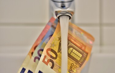 tap with running water and euro bills of 50, 20, 10 denominations