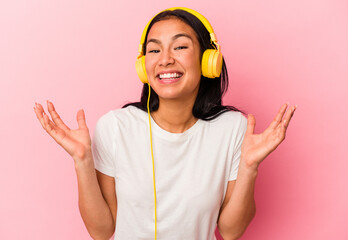 Young Venezuelan woman listening to music isolated on pink background receiving a pleasant surprise, excited and raising hands.