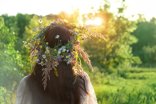 Woman in flower wreath outdoor, rear view. Floral crown, symbol of summer solstice. traditional Slavic ceremony on Midsummer, wiccan Litha sabbath. pagan holiday Ivan Kupala