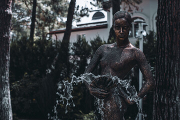 A fountain in the form of a metal statue of a woman holding a fan in her hands