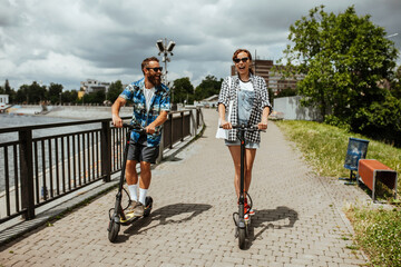 Portrait of a modern young couple on vacation having fun riding on electric scooters through the city. © San4ezz007