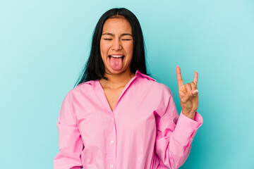 Young Venezuelan woman isolated on blue background showing rock gesture with fingers