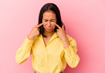 Young Venezuelan woman isolated on pink background crying, unhappy with something, agony and...