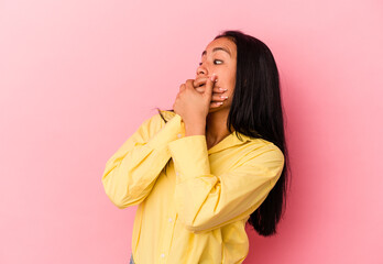 Young Venezuelan woman isolated on pink background thoughtful looking to a copy space covering mouth with hand.