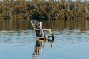Green plastic chair placed in the water, Wandandian Creek, NSW, July 2021