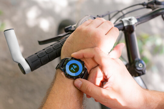 Hands of a man with a smartwatch in close-up while cycling.