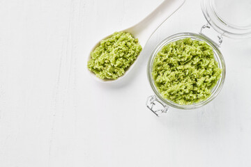 Homemade green body scrub in a glass jar on a white background. Top view