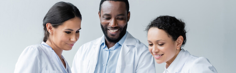 Smiling interracial doctors looking down in clinic, banner