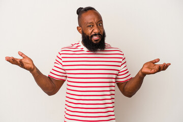 African american man with beard isolated on pink background doubting and shrugging shoulders in...