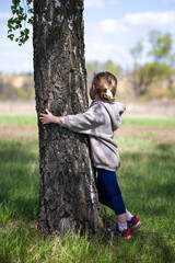 a little girl hugs a tree