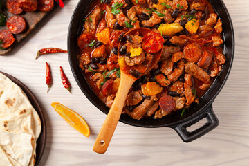 Pork stew with chorizo and black beans. Served with orange and seasoned with hot chili peppers....