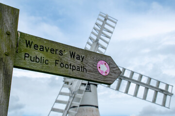 Close up of Weavers Way public footpath sign at Thurne in the Norfolk Broads. Against the backdrop of a blurred/bokeh Thurne Mill.