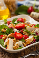Delicious salad with fried chicken, blue cheese, strawberries and walnuts. Front view.