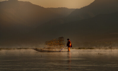 Silhouette fishermen catches fish for food in sunrise rays at Inle lake ,Myanmar .Intha people lifestyle with early morning sun sky.