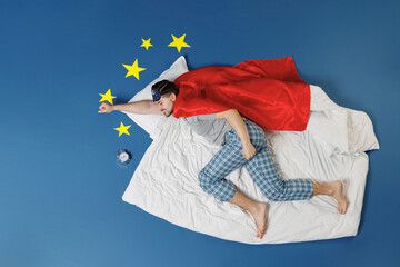 Full length top view powerful young man in pajamas jam sleep mask superhero suit rest relax home lies make fly gesture isolated on dark blue sky background Night bedtime supernatural abilities concept - obrazy, fototapety, plakaty