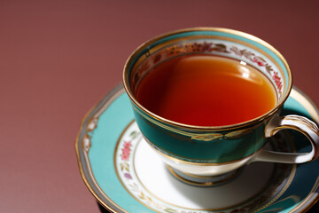 Hot tea in an antique cup and saucer on a brown background
