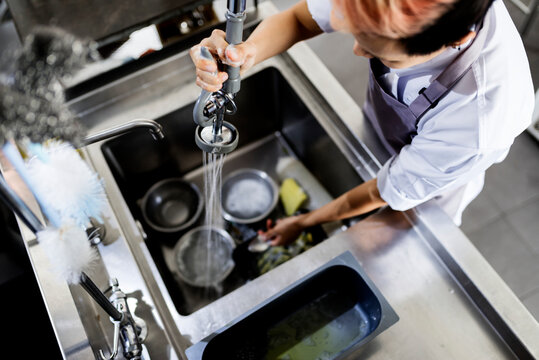 Top view of kitchen staff washing utensils at sink