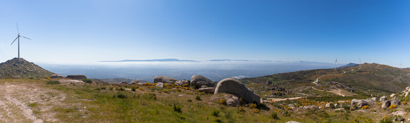 Panoramic and amazing view from the top of the Caramulo mountains over the Serra da Estrela mountains, wind turbines and granitic rocks, undergrowth in Viseu - obrazy, fototapety, plakaty