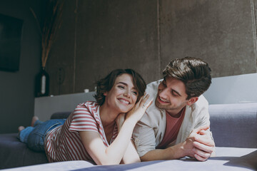 Full body young couple two friends woman man in casual clothes lying on sofa watch movie spend free time together hug put head on shoulder rest indoors at home flat together People lifestyle concept.