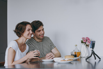 Young happy smiling couple two woman man 20s in casual clothes sit by table eat pancake talk video...