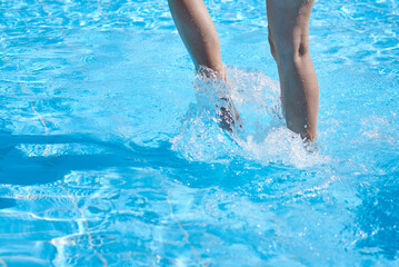 Close up of boy legs in swimming pool with splashes. Summer relax