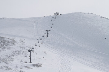 The chairlift stretches to the top of the ski resort. The mountainside is covered with traces of skis and snowboards