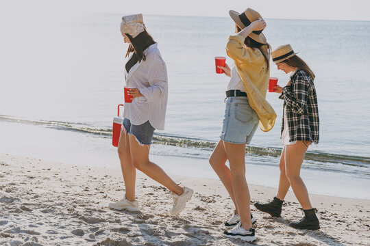 Full Body Side View Female Friends Young Women In Straw Hat Summer Clothes Hang Out Together Carry Food In Picnic Refrigerator Glasses Outdoor On Sea Beach Background People Vacation Journey Concept