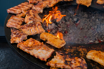Process of cooking fresh juicy meat steaks on brazier at summer local food market - close up view. Outdoor cooking, gastronomy, cookery, street food concept