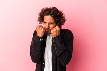 Young caucasian man isolated on pink bakcground throwing a punch, anger, fighting due to an argument, boxing.