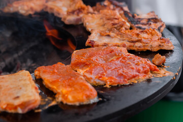 Close up: process of cooking fresh juicy meat steaks on brazier at summer local food market. Outdoor cooking, gastronomy, cookery, street food concept