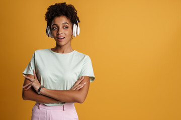 Young black woman with headphones smiling and holding her arms crossed
