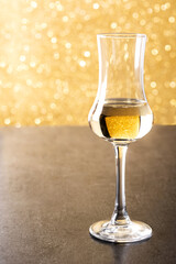 Italian golden grappa drink on yellow bright background. Copy space	