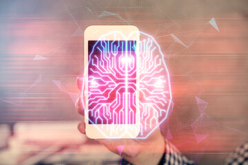 Double exposure of man's hand holding and using a digital device and brain hologram drawing. Data...
