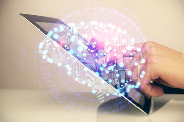 Double exposure of man's hand holding and using a digital device and brain hologram drawing. Data concept.