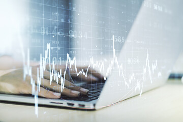 Abstract creative financial graph with hand typing on laptop on background, financial and trading...