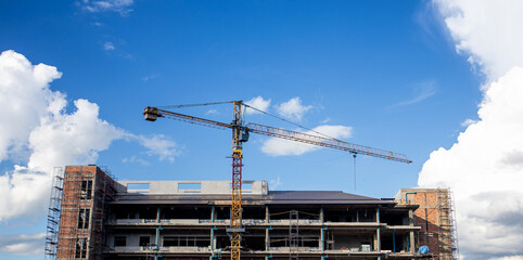 Construction of a tall building with cranes, construction crane, building, and blue sky. industrial concept