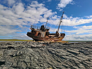 Fototapeta na wymiar A fishing vessel thrown by a storm on the shores of the Barents Sea.