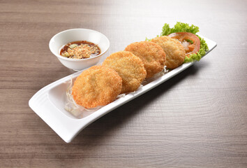 deep fried seafood crispy fish cake with spicy chilli sauce on wood table asian Thai appetiser halal menu