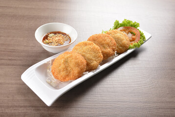 deep fried seafood crispy fish cake with spicy chilli sauce on wood table asian Thai appetiser halal menu
