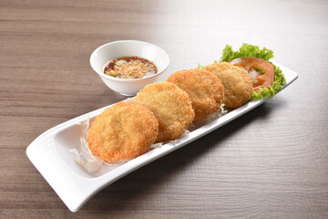deep fried seafood crispy fish cake with spicy chilli sauce on wood table asian Thai appetiser halal menu