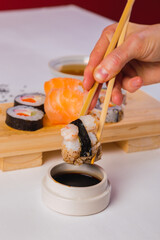 Close-up of chopsticks taking a portion of sushi roll and soy sauce.
