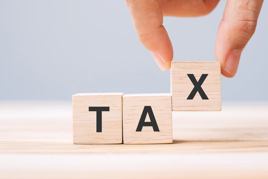 hand holding wood cube block with TAX text . Financial, Management, Economic, business and time to tax concept