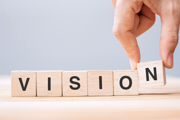 Business man hand holding wooden cube block with VISION business word on table background. strategy, Mission and core values concept