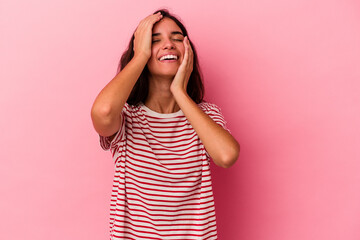 Young caucasian woman isolated on pink background laughs joyfully keeping hands on head. Happiness concept.