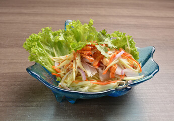 cold thai style spicy chilli sauce papaya and mango vegetable salad and shrimp in bowl on wood table asian Thai appetiser halal menu