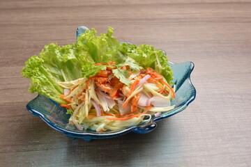 cold thai style spicy chilli sauce papaya and mango vegetable salad and shrimp in bowl on wood table asian Thai appetiser halal menu