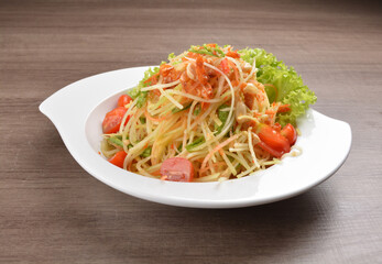 cold thai style spicy chilli sauce papaya and mango vegetable salad and shrimp in bowl on wood table asian Thai appetiser halal menu