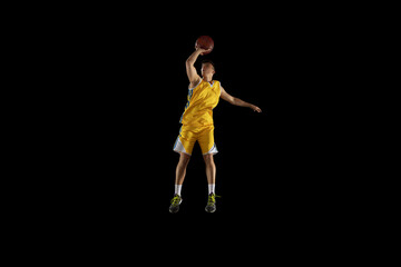 Fototapeta na wymiar Young man, basketball player with a ball training isolated on dark black studio background. Advertising concept. Fit Caucasian athlete practicing with ball.