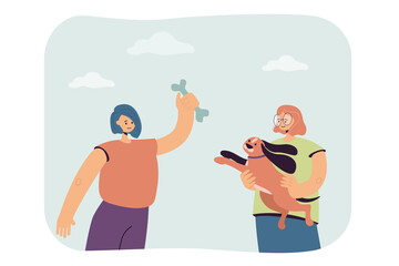 Girls playing with dog flat vector illustration. One woman holding pet in her arms, second holding treat, giving it bone. Animal, pet, friendship, communication, happiness concept for banner design